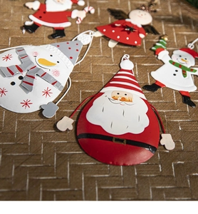 Flat lay of colorful painted metal Christmas ornaments like Santa and snowmen on woven texture