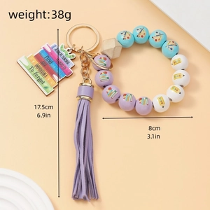 Detail of teacher-themed beaded keychain with purple tassel and engraved wooden charm