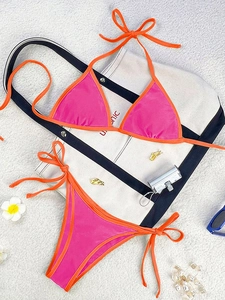 Detail of rose red and bright orange bikini set with ties and tropical props