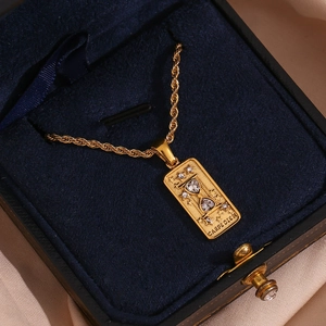 Detailed macro view of 18K gold tarot pendant with hourglass and zircons on twist chain