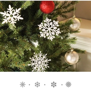 Close-up of white 3D snowflakes and glittery red gold ornaments on a Christmas tree