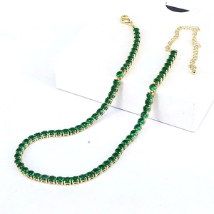 Detail of adjustable gold tennis necklace with square green cubic zirconia stones