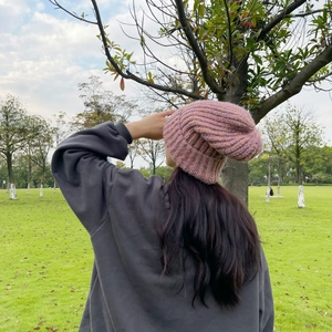 Outdoor shot of a thick pink knit beanie showing warm winter texture from a back view