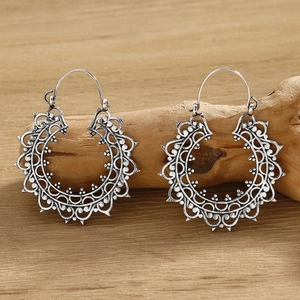 Macro view of vintage silver hollow round earrings displayed on natural wood surface
