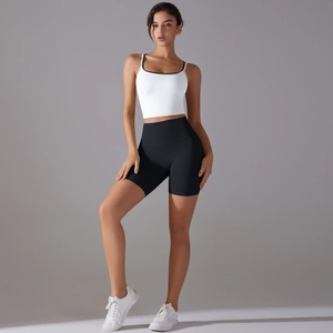 Detail of white cross-back yoga tank top with black trim and high-waisted gym shorts