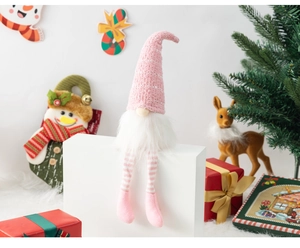 Pink faceless gnome doll with striped legs and knit hat in a festive Christmas scene