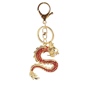 Porte-clés dragon doré orné de strass rouges avec anneau sur un fond blanc pur