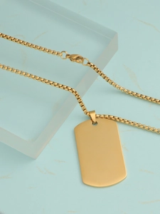 Detailed view of a golden stainless steel dog tag pendant necklace on a marble surface