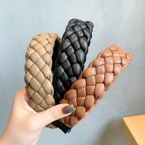 Detailed view of three braided PU leather headbands in khaki, black, and brown colors