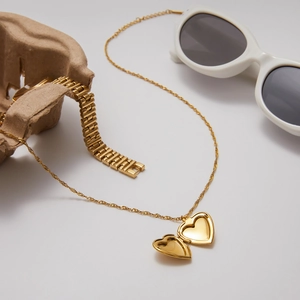 Golden titanium steel heart locket necklace with flat chain on white background