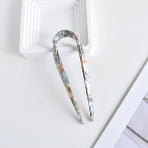 Detail view of U-shaped hair pin featuring blue and orange marble acetate texture