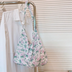 Primer plano de bolso de algodón con estampado de rosas moradas colgado en rack