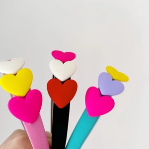 Close-up of colorful heart sponge headbands for children in pink, black, and teal colors