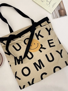 Minimalist beige canvas tote bag with black letter print and yellow smiley face graphic