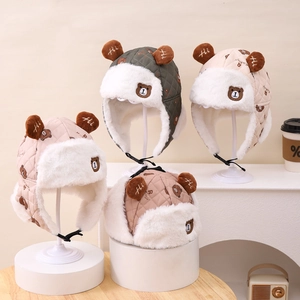 Dettaglio di colbacchi invernali trapuntati con fodera in peluche e ricamo di orso