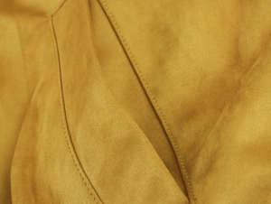 Detailansicht der senfgelben Bomberjacke aus Wildlederimitat mit feiner Naht und Textur