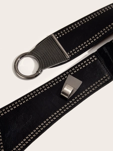 Détail d'une large ceinture punk noire avec clous argentés et boucle en métal ronde