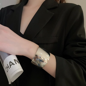 Close-up of minimalist polished silver knotted open cuff bracelet on a model's arm
