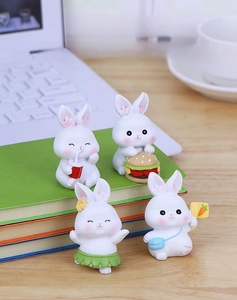 Set of four cute resin rabbit figurines on a desk featuring creative miniature poses