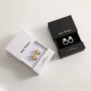 Detail showing elegant gold hoop earrings and pearl studs with branded jewelry gift boxes