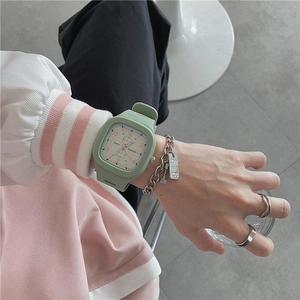 Detail of green square quartz watch with silicone strap and silver chain bracelet