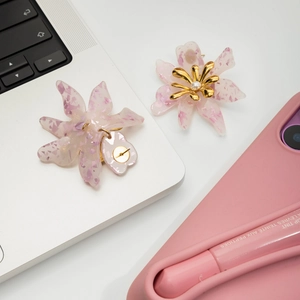 Detailaufnahme der 18K vergoldeten Blumenohrringe mit rosa Acrylharz und weißen Perlen