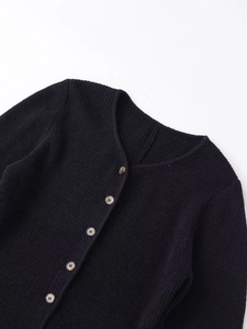 Close-up of rib-knit texture and amber-textured buttons on black round neck cardigan