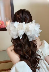 Detailed view of white lace bow hair clip with 3D flowers and pearls on long hair