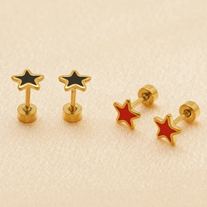 Star-shaped stainless steel earrings with black and red enamel on beige fabric background