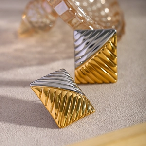 Macro shot of square two-tone gold and silver earrings with fine textured stripes