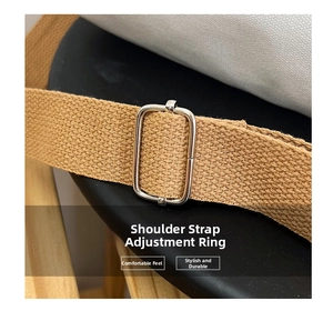 Detail of adjustable silver buckle and brown woven strap on a canvas handbag