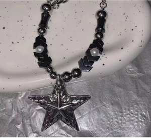 Détail du collier étoile Y2K avec perles métalliques sur un plateau en céramique