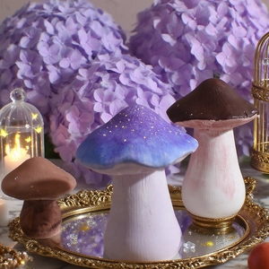 Tre funghi decorativi in resina su un vassoio dorato con fiori di ortensia viola