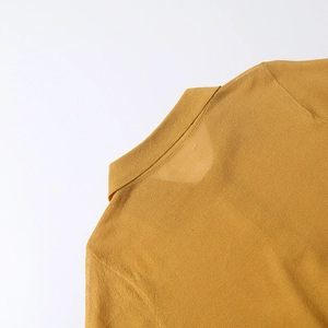 Detailed macro view of the knitted polo collar and shoulder seam in yellow fabric