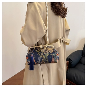 Detail of floral handbag with metal frame, pearl chain strap and tassel charm