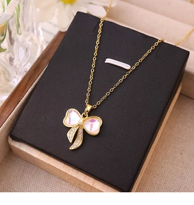 Dettaglio di una collana a fiocco dorata con cristallo rosa e zircone in regalo