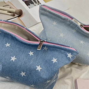 Detail of denim bow cosmetic bags with star pattern and smooth pink zipper closure