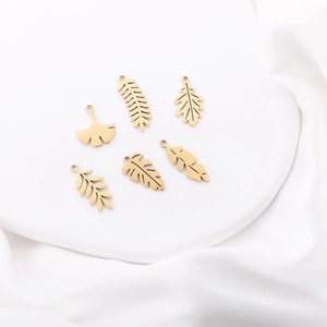 Detailed close-up of golden stainless steel hollow leaf pendants for DIY jewelry