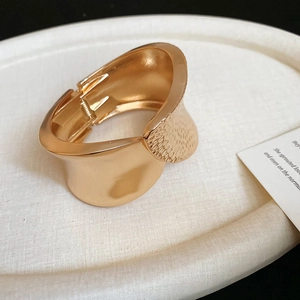 Detail of gold-tone irregular hammered texture cuff bracelet with spring hinge closure