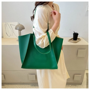 Deep green large PU tote bag shown as a crossbody bag on a model in an indoor setting