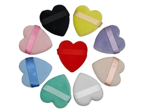 Colorful heart-shaped makeup powder puffs in a circular arrangement on white background