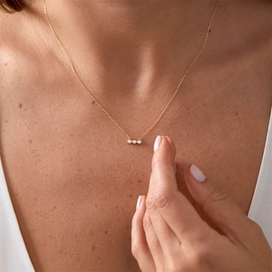 Vue détaillée d'un collier en or avec trois zircons ronds portés par un mannequin femme
