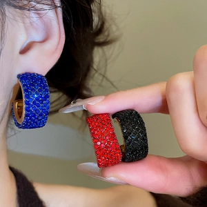 Detail view of vintage geometric C-shaped earrings with red and blue crystals in gold setting