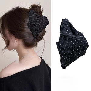 Detail of black and white polka dot fabric bow hair claw clip for elegant hairstyles