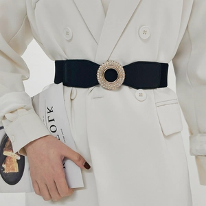 Detailed view of women's elastic waist belt with sparkling rhinestone buckle on white blazer
