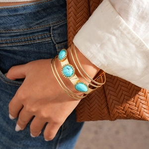 Detail of bohemian gold multilayer bracelet set featuring turquoise stones on a model wrist