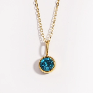 Close-up of golden necklace with circular blue gemstone pendant on white background