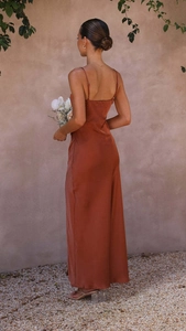 Detail of cross-back spaghetti straps on a rusty orange satin maxi slit dress