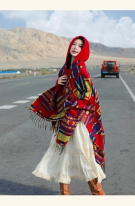 Detail of red oversized hooded shawl with ethnic geometric patterns and tassel fringe edge