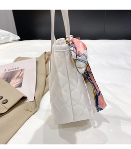 Close-up of white quilted tote bag featuring a pink silk scarf on the top handle